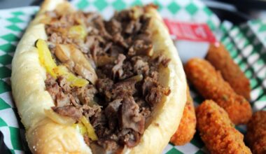 Cheesesteak featuring meat and peppers on a split bun with a side of cheese fries.