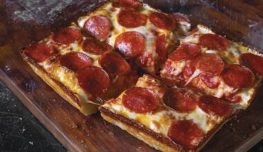 Overview of a pepperoni pizza on a dark brown cutting board.