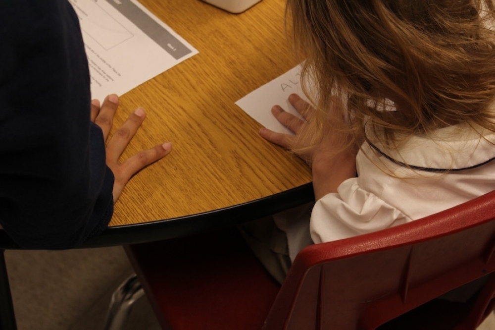 student writing on paper at desk