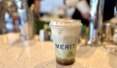 A Merit Coffee iced matcha sitting on the counter in front of the baristas at work