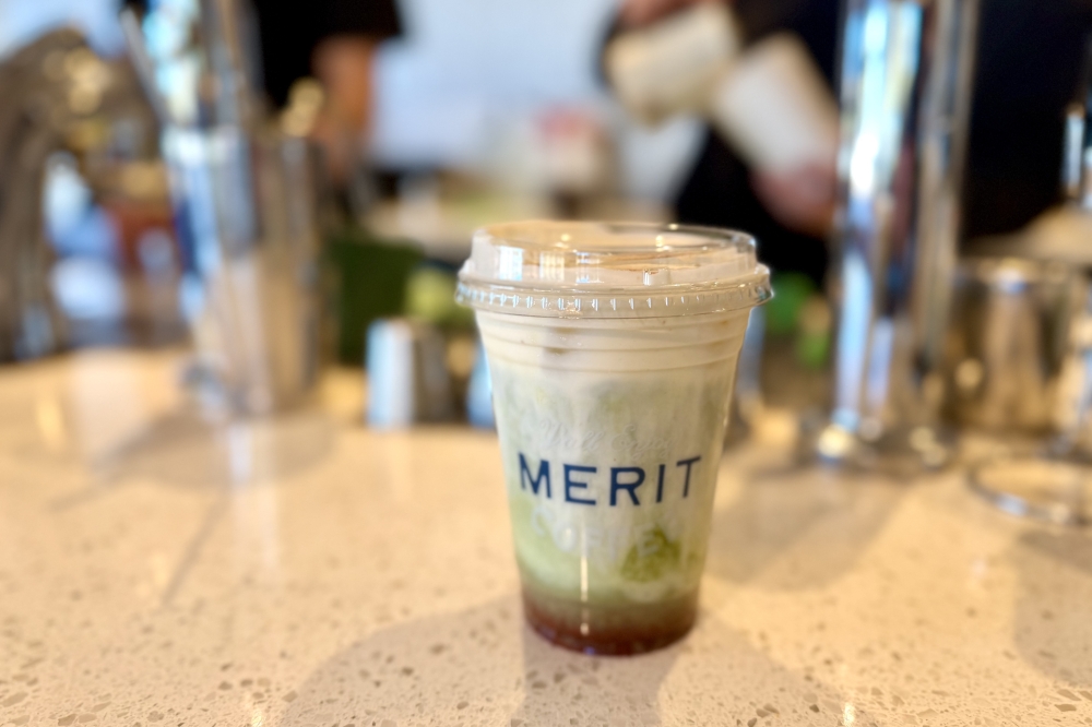 A Merit Coffee iced matcha sitting on the counter in front of the baristas at work