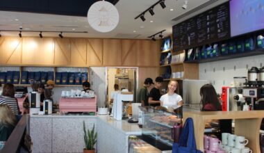 Baristas stand behind the counter at a coffee shop