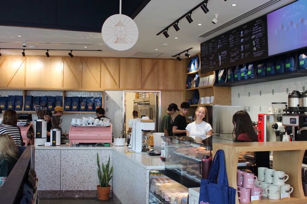 Baristas stand behind the counter at a coffee shop