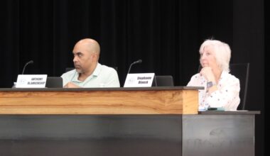 The board members sit at a podium