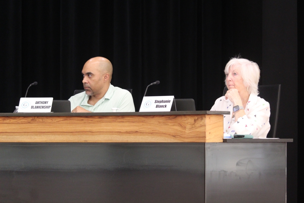 The board members sit at a podium