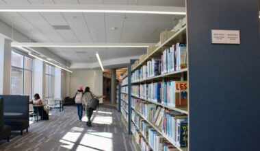 people walking near a shelf of books at a library