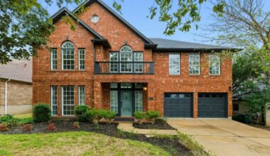 Brick home with blue doorway and iron balcony in 78739