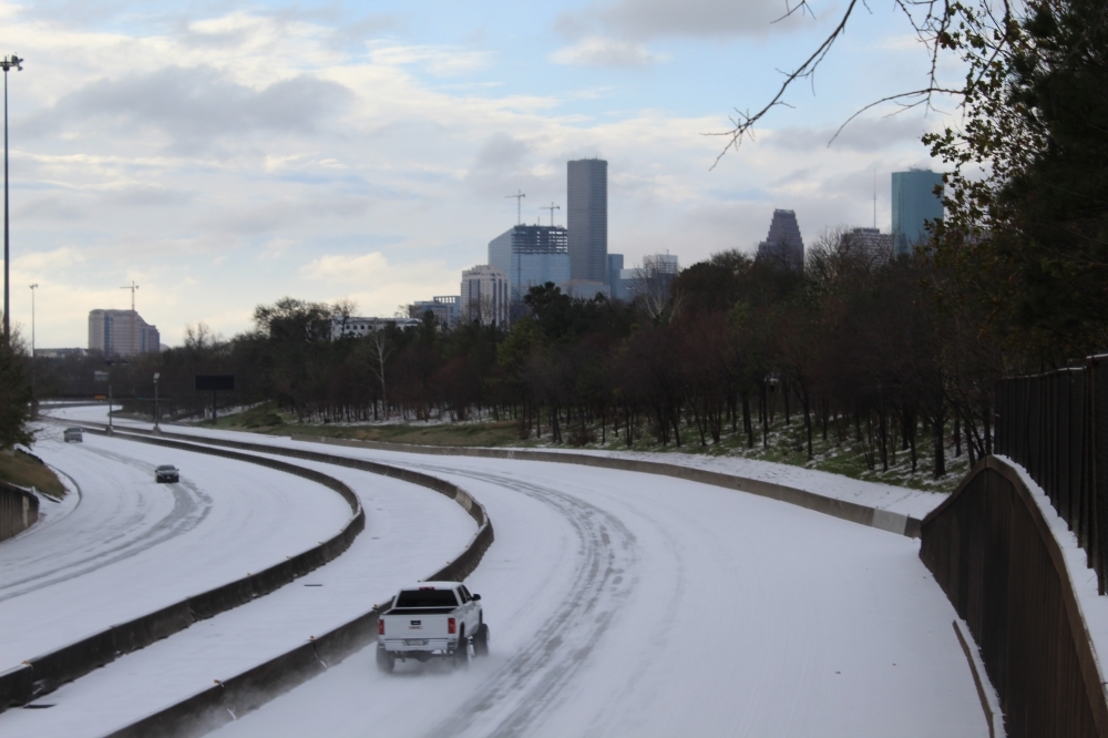 A white truck drives on the largely empty, snow-covered I-45 in Houston in February 2021.