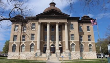 The Hays County courthouse stands tall with four large white pillars and a dome top.