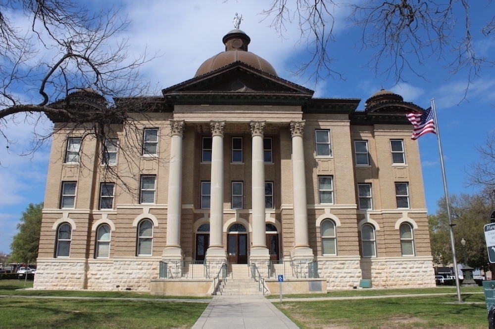 The Hays County courthouse stands tall with four large white pillars and a dome top.