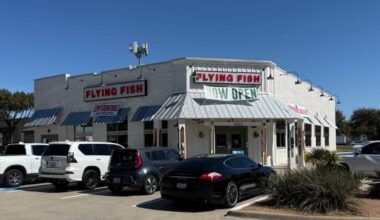 Exterior of a freestanding building featuring Flying Fish signage and now open banners.