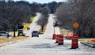 Construction cones sit along the roadway near a drainage improvement project.