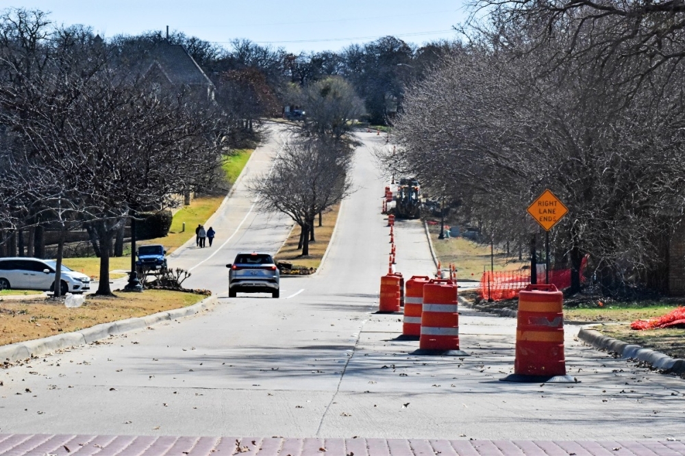 Construction cones sit along the roadway near a drainage improvement project.