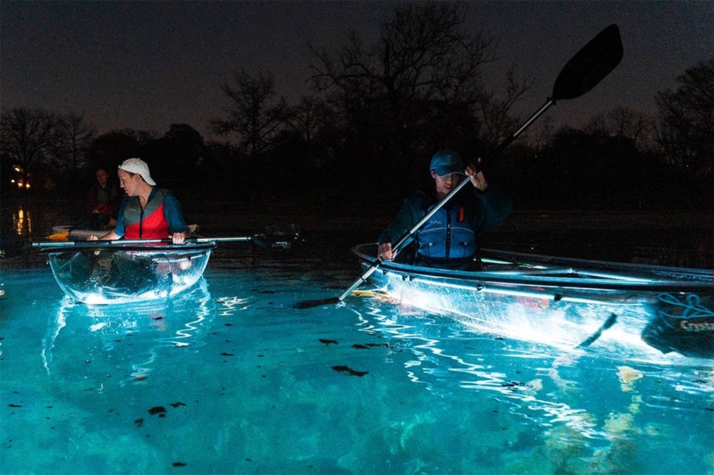Two peopl ein kayaks are shown. The kayaks light up on the bottom with the blue water.