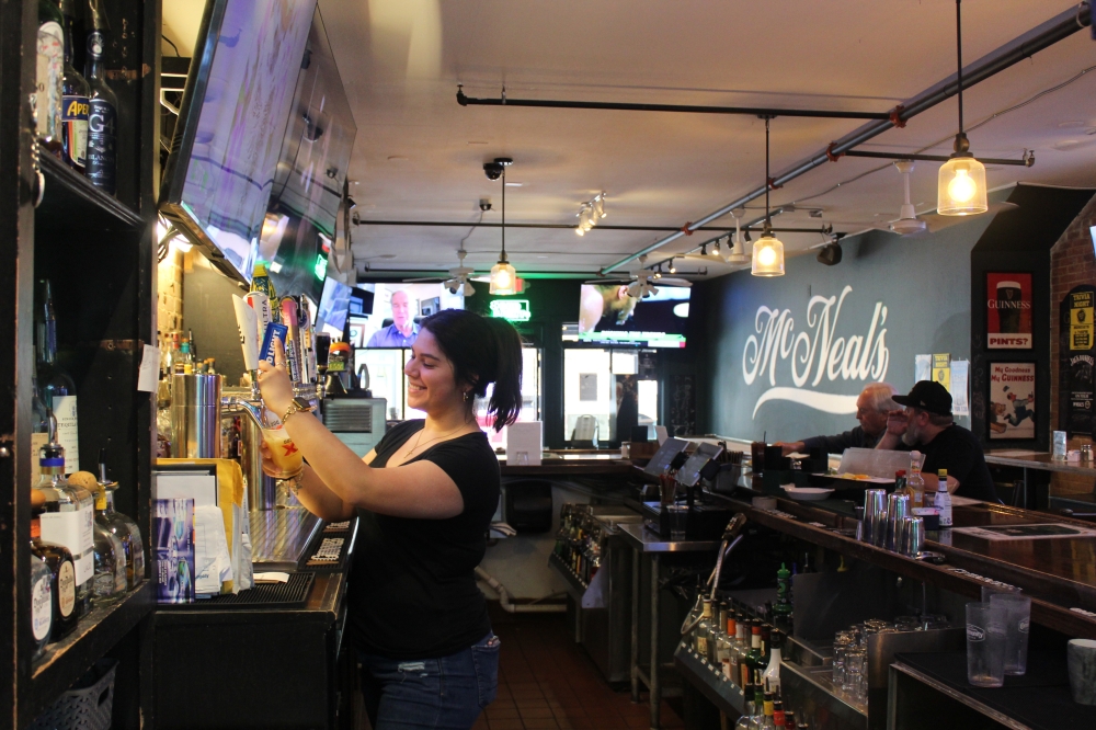 Rachel, a bartender at McNeal’s Tavern in downtown Plano, serves patrons. (Michael Crouchley/Community Impact)