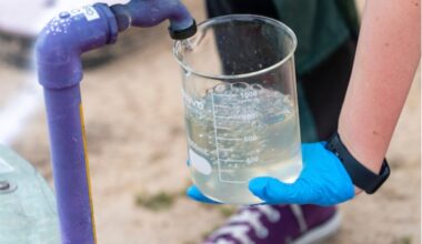 A worker fills a beaker with water from a land well.