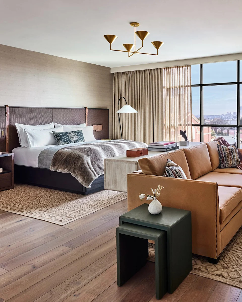 luxury hotel room featuring plush bed and brown leather couch