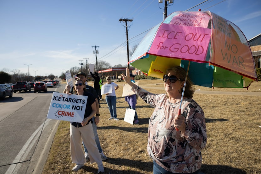 Mitzy Andersen of Little Elm holds an umbrella with signs saying “ICE OUT for GOOD”, “NO...