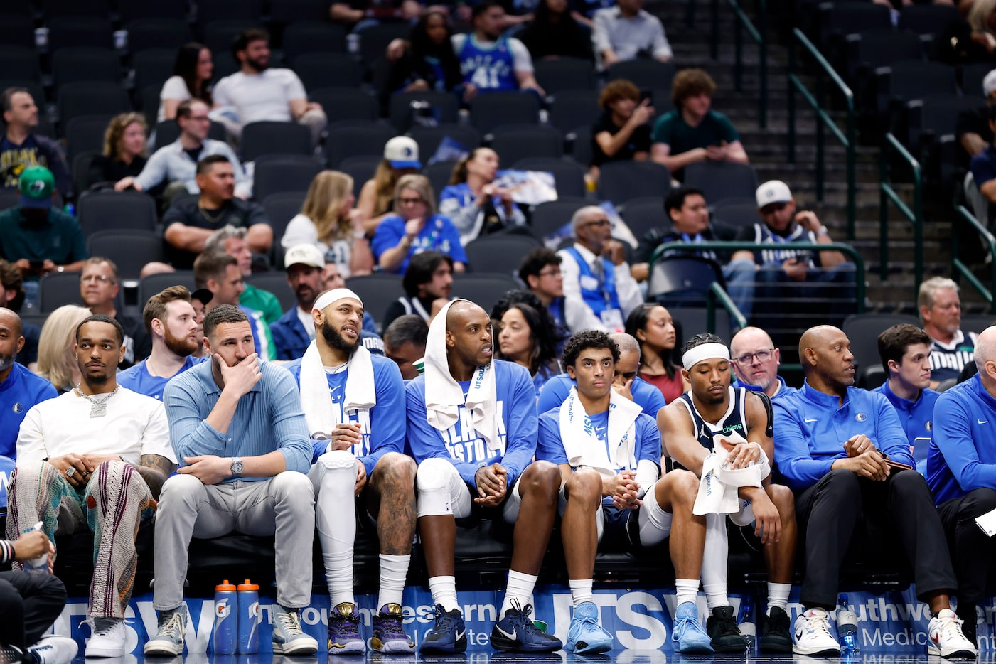 Dallas Mavericks injured and healthy players line the bench as fans file out in the fourth...