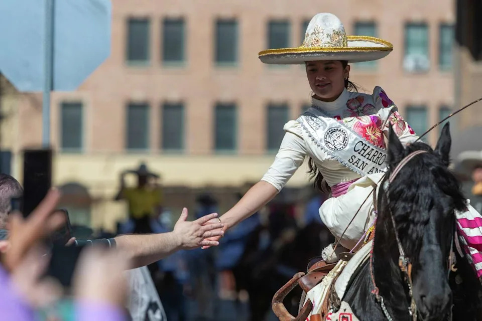 The Charro Queen, with the San Antonio Charro Association, high-fives a crowd member during the Western Heritage Parade on Saturday, Feb. 7, 2026. (Blaine Young/Contributor)