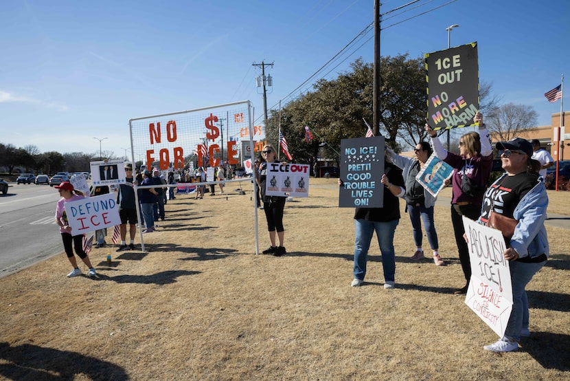 Protestors hold signs during a No Kings and anti-ICE demonstration on W University Dr near...