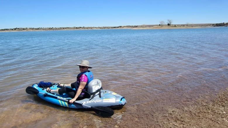 A smiling woman paddles a kayak at Sumner Lake State Park.