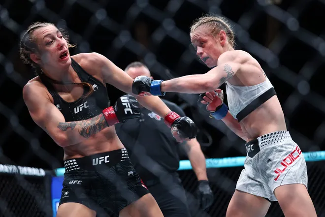 Feb 21, 2026; Houston, Texas, USA; Juliana Miller (red gloves) fights Carli Judice (blue gloves) in a womens flyweight bout during UFC Fight Night at Toyota Center. Mandatory Credit: Troy Taormina-Imagn Images