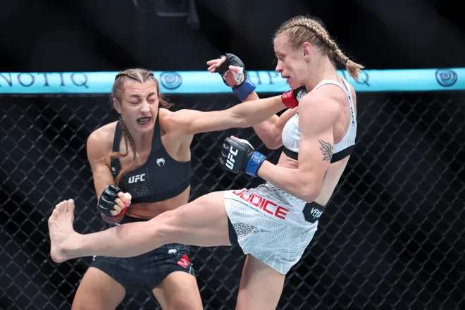 Feb 21, 2026; Houston, Texas, USA; Juliana Miller (red gloves) fights Carli Judice (blue gloves) in a womens flyweight bout during UFC Fight Night at Toyota Center. Mandatory Credit: Troy Taormina-Imagn Images