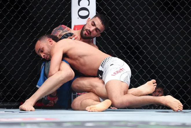 Feb 21, 2026; Houston, Texas, USA; Jordan Leavitt (red gloves) fights Yadier del Valle (blue gloves) in a featherweight bout during UFC Fight Night at Toyota Center. Mandatory Credit: Troy Taormina-Imagn Images