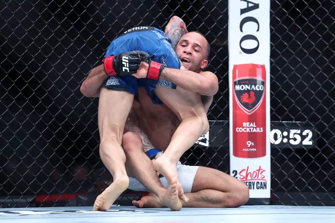 Feb 21, 2026; Houston, Texas, USA; Jordan Leavitt (red gloves) fights Yadier del Valle (blue gloves) in a featherweight bout during UFC Fight Night at Toyota Center. Mandatory Credit: Troy Taormina-Imagn Images