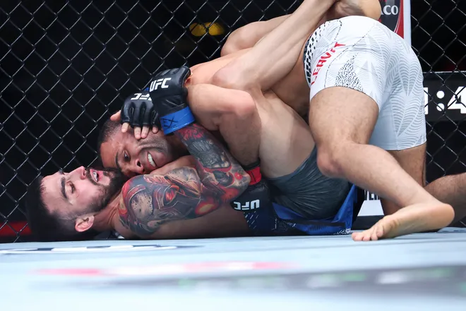 Feb 21, 2026; Houston, Texas, USA; Jordan Leavitt (red gloves) fights Yadier del Valle (blue gloves) in a featherweight bout during UFC Fight Night at Toyota Center. Mandatory Credit: Troy Taormina-Imagn Images