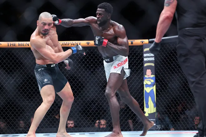 Feb 21, 2026; Houston, Texas, USA; Chidi Njokuani (red gloves) fights Carlos Leal (blue gloves) in a welterweight bout during UFC Fight Night at Toyota Center. Mandatory Credit: Troy Taormina-Imagn Images