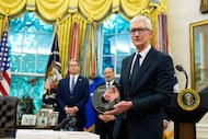 Apple CEO Tim Cook holds a gift from President Donald Trump during an announcement about...