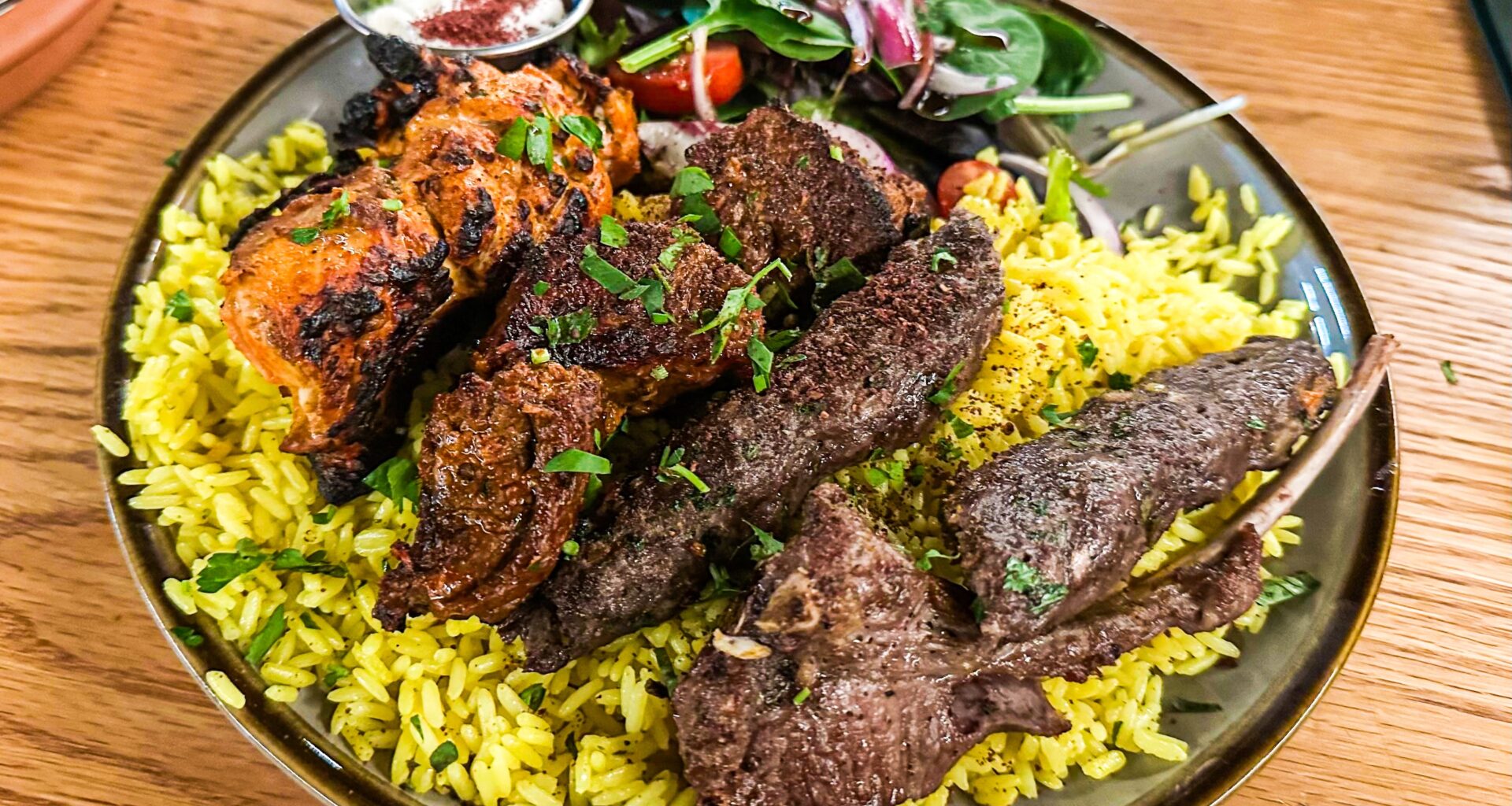 A bowl of rice topped with lamb and beef skewers from Ayat.