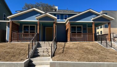 Image a two-story duplex with two townhomes. The exterior is blue with brown wood railings and columns on the covered front porch.