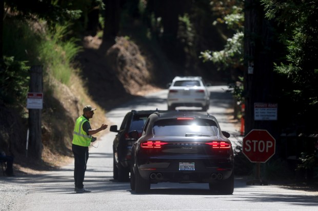 A security guard talks with a driver at the main entrance of Bohemian Grove in Monte Rio, Calif. on Thursday, July 28, 2022. (Beth Schlanker/The Press Democrat)