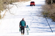 Sledders walk home from riding down ice-laden Brown Blvd at N. Collins St. Arlington school...