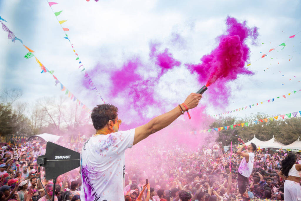 Image shows someone on stage at Holi Houston with a color cannon