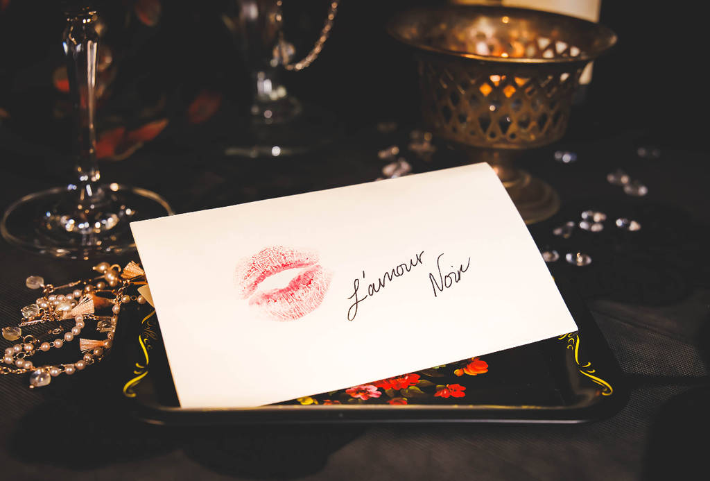 Image shows a display of cocktails with a letter featuring the words "L'Amour Noir" with a kiss imprint.