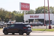 Traffic passes along South Buckner Boulevard by a Tricolor Auto car dealership on Thursday,...