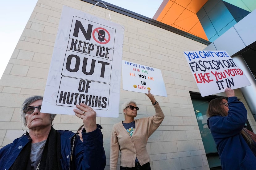 Demonstrators hold signs during a protest outside Hutchins City Hall prior to a special...