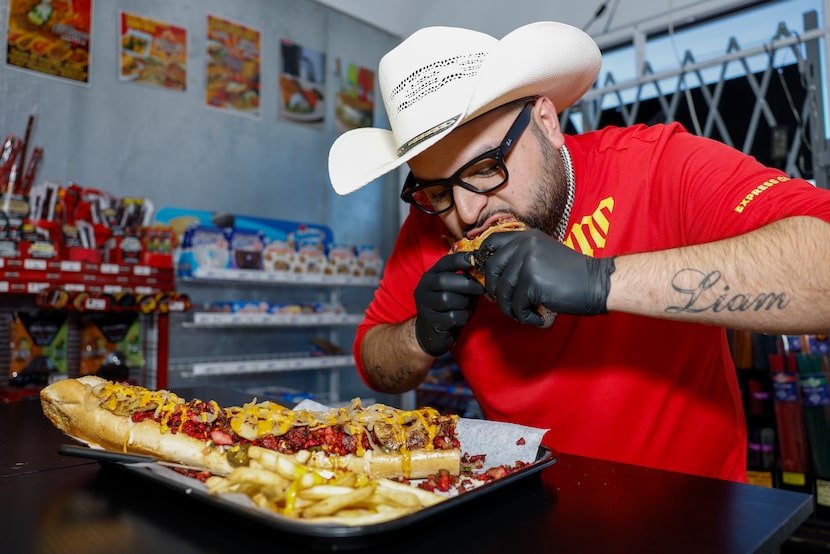 El Reyno Taqueria owner Jose Reyna takes a bite of a two-foot long hot dog at his...