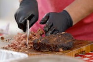 Mark Montemayor cuts brisket at the booth of Panther City BBQ from Fort Worth during Lone...