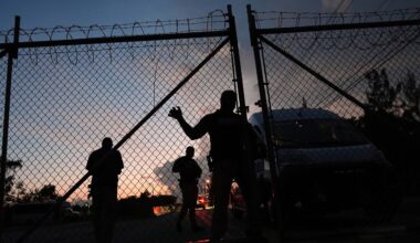 Krome Detention Center officers man an entrance gate as people hold a vigil outside to recognize those who have died in U.S. Immigration and Customs Enforcement custody, as well as those affected by mass deportations, Saturday, May 24, 2025, in Miami. (AP Photo/Rebecca Blackwell)