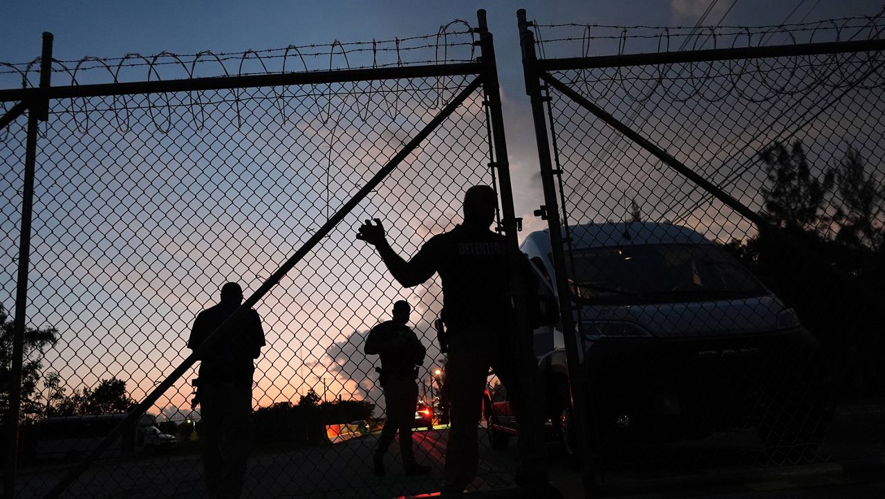 Krome Detention Center officers man an entrance gate as people hold a vigil outside to recognize those who have died in U.S. Immigration and Customs Enforcement custody, as well as those affected by mass deportations, Saturday, May 24, 2025, in Miami. (AP Photo/Rebecca Blackwell)