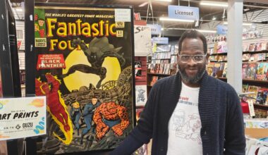 Evan Narcisse, the framing story writer of the Black Panther 60th Anniversary Special, standing next to a poster of the first appearance of Black Panther at Austin Books & Comics in Austin, Texas. (Spectrum News 1/Rhett Brady)