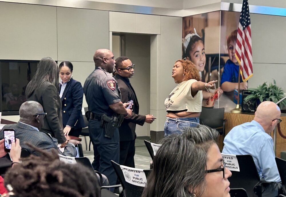 A woman fights with an HISD officer at the tense board meeting