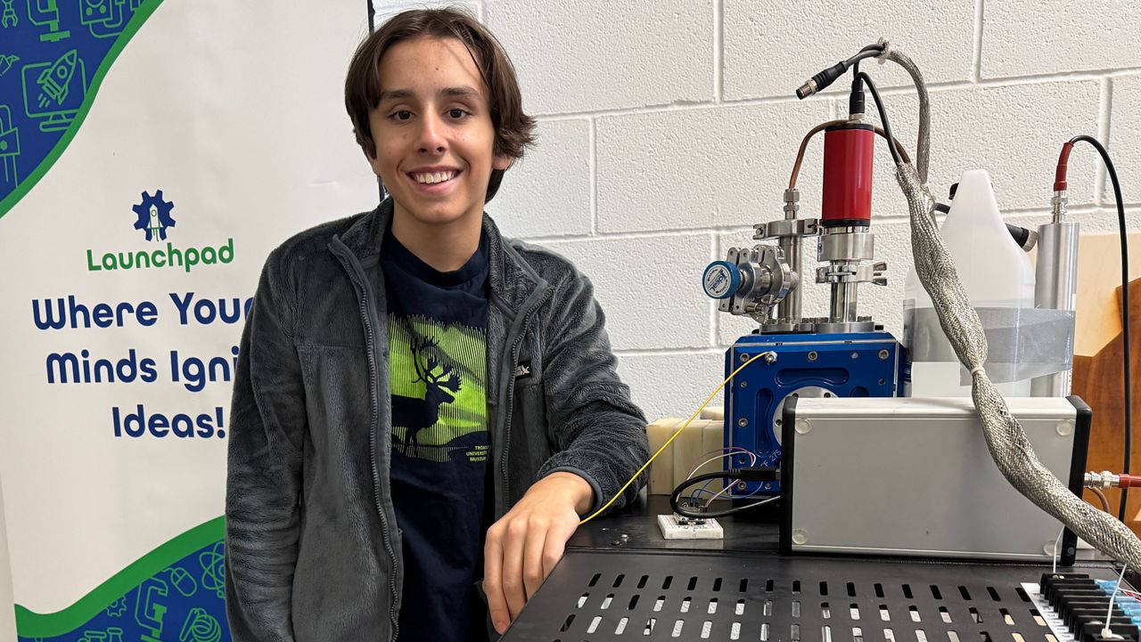 Aidan McMillan stands next to his tabletop fusor that he's hoping will help him be a new Guinness World Record Holder.