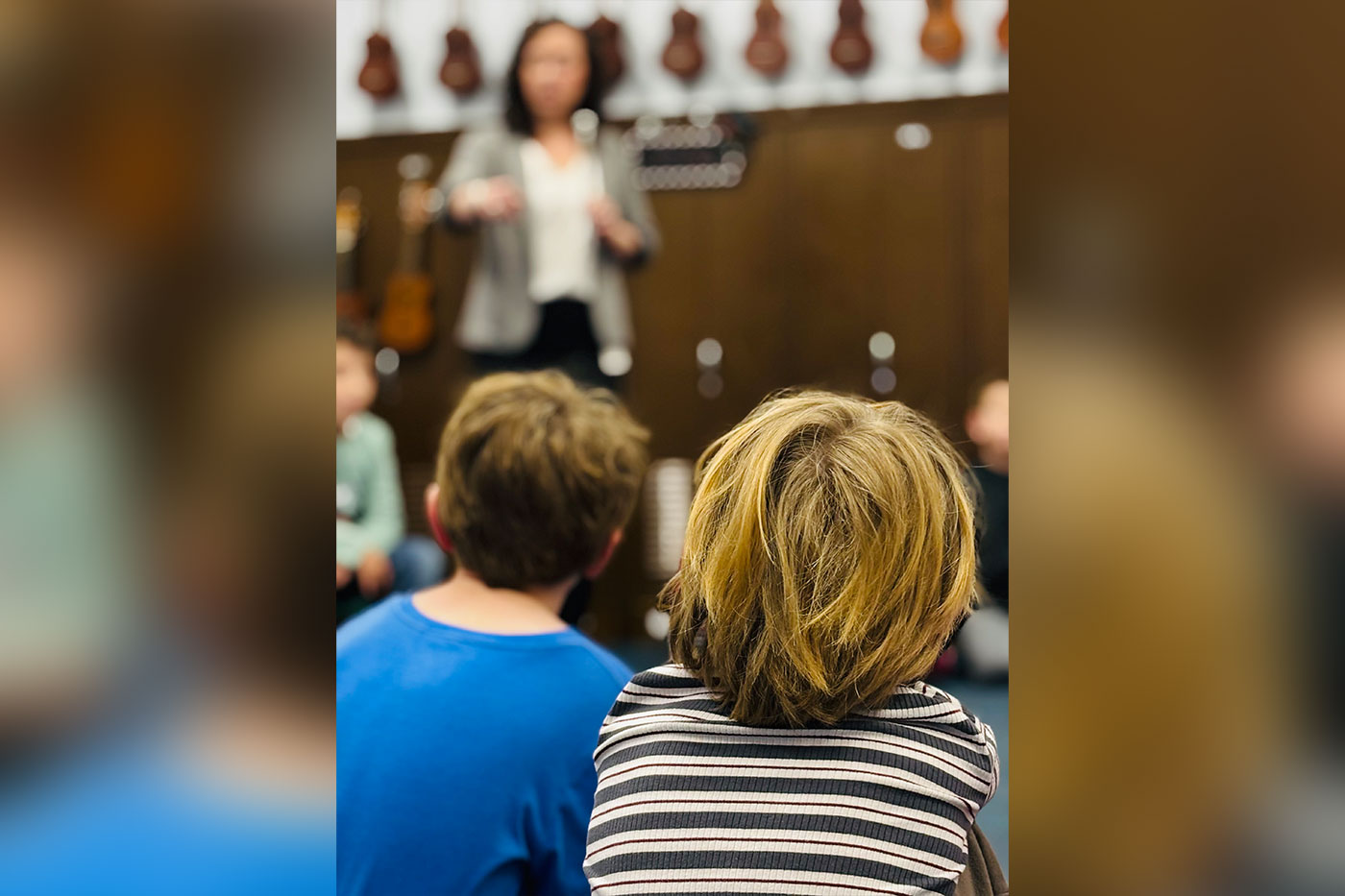 Algate at the front of the classroom as two boys look on. 