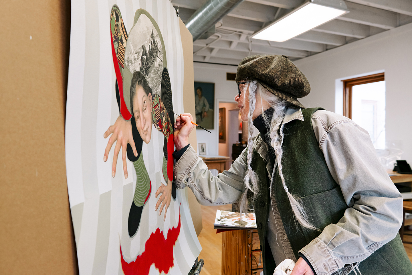 A photograph of artist Julie Speed working on a painting in her studio.
